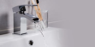 Closeup shot of water flowing from a basin mixer tap in the bathroom