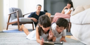 happy-parent-watching-little-kids-lying-on-floor-in-living-room-and-using-digital-gadgets-together-min-1075x605-1