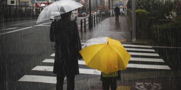 Family crossing a road on rainy day