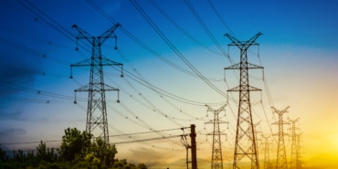 Sun setting behind the silhouette of electricity pylons