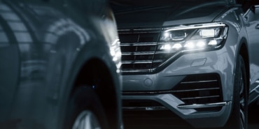 Powerful headlights. Particle view of modern luxury cars parked indoors at daytime