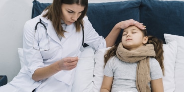 close-up-female-doctor-sitting-near-patient-girl-looking-thermometer