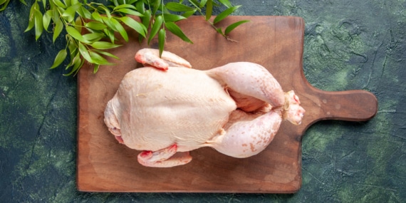 top-view-fresh-chicken-with-green-leaves-dark-blue-surface