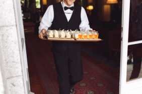 Waiter carries dish with snacks walking to the backyard