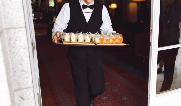 Waiter carries dish with snacks walking to the backyard